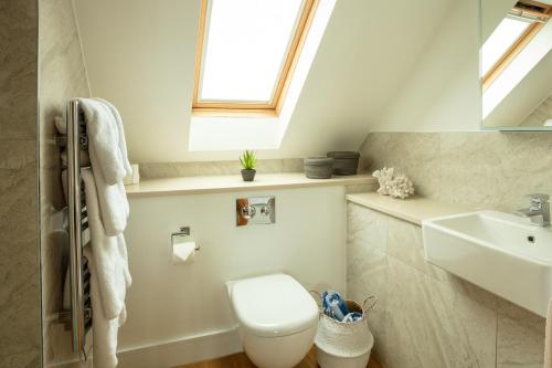 baño con aseo y lavabo y ventana en La Pulente Cottages, en St Brelade