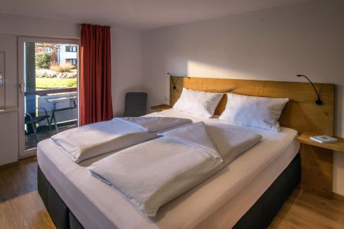 1 dormitorio con 1 cama grande con sábanas blancas en Appartement-Hotel-Allgayer en Oy-Mittelberg