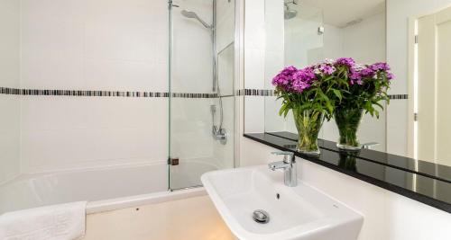 ein Badezimmer mit einem Waschbecken und einer Vase aus lila Blumen in der Unterkunft High Seas - NEW LISTING in Brixham