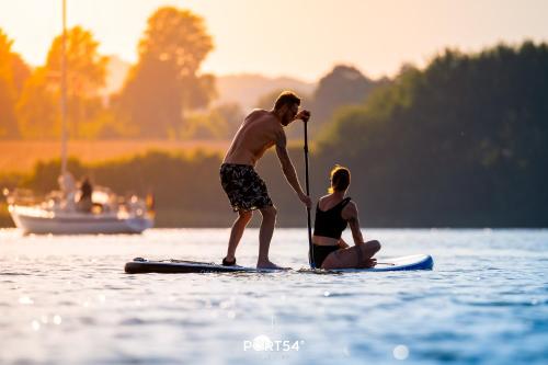 a man and a woman on a paddle board in the water at Sandpiper in Gelting