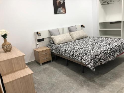 a bedroom with a bed with a black and white comforter at Apartamento La Plana II in Castellón de la Plana