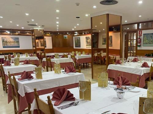 uma sala de jantar com mesas brancas e guardanapos vermelhos em Hotel Folch em Sant Julià de Lòria