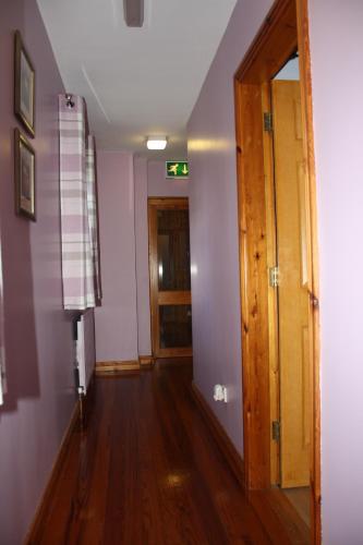 a hallway with purple walls and a wooden door at The Coach Inn in Strabane