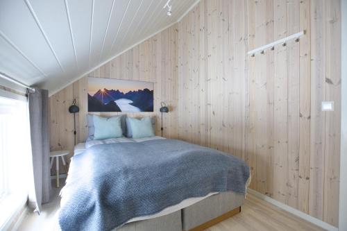 ein Schlafzimmer mit einem Bett in einem Zimmer mit Holzwänden in der Unterkunft Cabin in Lofoten with spectacular view in Ballstad