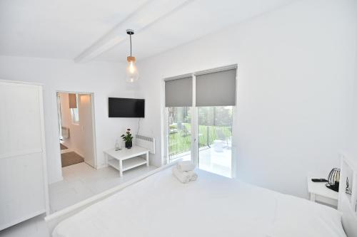 a white bedroom with a large bed and a television at MIRA by Atra in Teşila