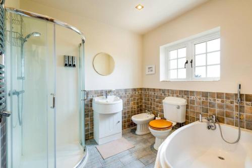 a bathroom with a tub and a toilet and a sink at Croft House Sleeps 8 ꕤ Country Views nr Salisbury in Salisbury