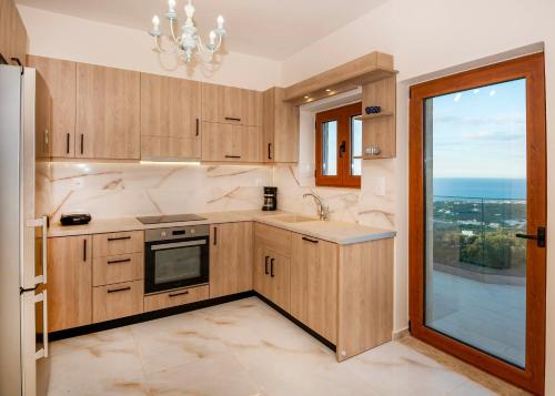 a kitchen with wooden cabinets and a large window at Maroulas Natura Palace in Giannoudi