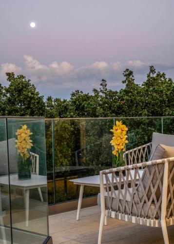 a balcony with a table and a bench and flowers at Maroulas Natura Palace in Giannoudi
