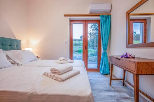 two beds in a room with a desk and a window at Maroulas Natura Palace in Giannoudi