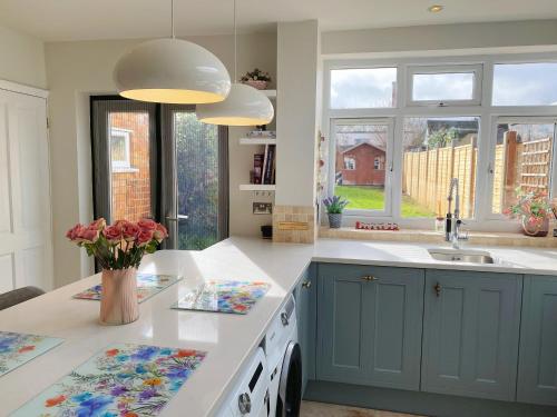 a kitchen with blue cabinets and flowers on the counter at Beautiful Victorian Home near central Oxford in Oxford