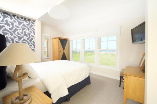 a bedroom with a bed with a lamp and a television at Point Cottages, Bamburgh in Bamburgh