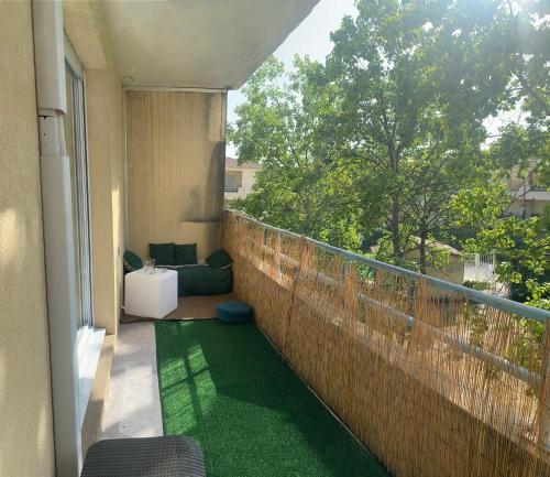 einen Balkon mit einem grünen Teppich an einer Ziegelmauer in der Unterkunft Studio avec terrasse in Montpellier