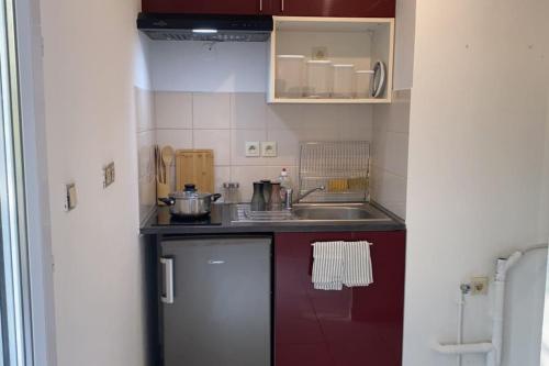 eine kleine Küche mit roten Schränken und einem Waschbecken in der Unterkunft Studio avec terrasse in Montpellier
