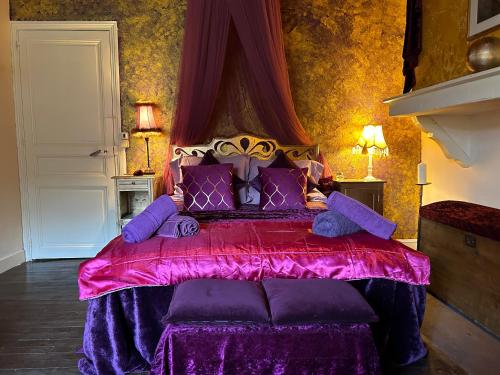 1 dormitorio con 1 cama grande con almohadas moradas en Les Contes, en Fougax-et-Barrineuf