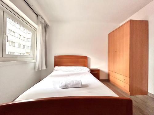 een slaapkamer met een bed met een houten hoofdeinde en een raam bij Vibes Coruña-Filipinas 4 in A Coruña