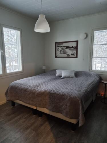 ein Schlafzimmer mit einem Bett und zwei Fenstern in der Unterkunft Villa Sara in Kalajoki