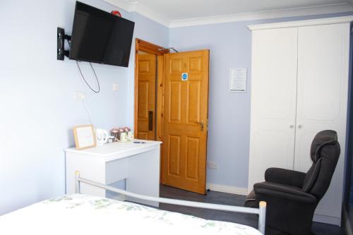 a bedroom with a bed and a chair and a television at The Coach Inn in Strabane