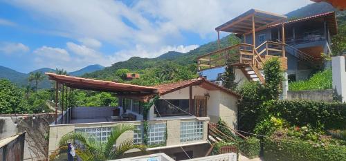 a house on a hill with mountains in the background at Pousada Encontro das Águas in Trindade