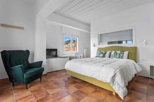 a bedroom with a large bed and a green chair at Hotel Roumani in Spetses