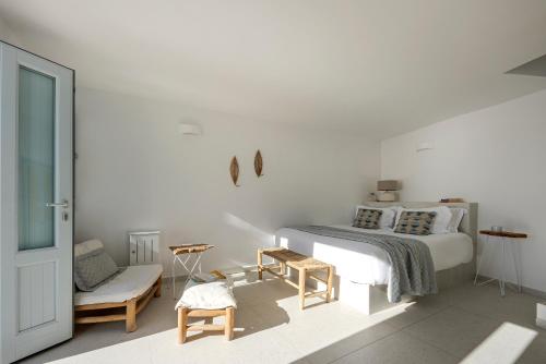 - une chambre blanche avec un lit et une chaise dans l'établissement Big Blue Villa by Caldera Houses, à Oia