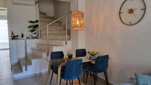 a dining room with a glass table and blue chairs at Eos House in Loutra