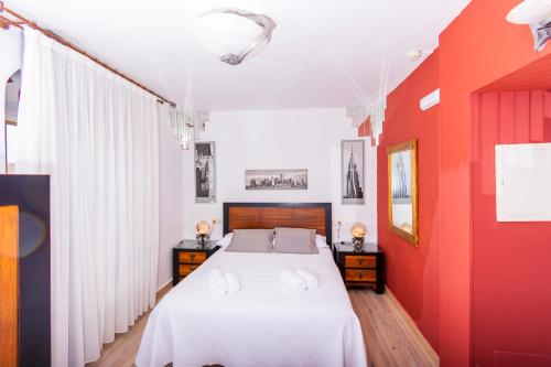 a bedroom with a white bed and red walls at Hotel Utopía in Benalup Casas Viejas