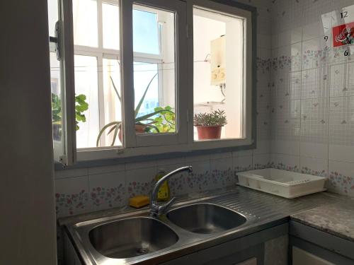 eine Küche mit einem Waschbecken und zwei Fenstern in der Unterkunft Casa melo in Martil
