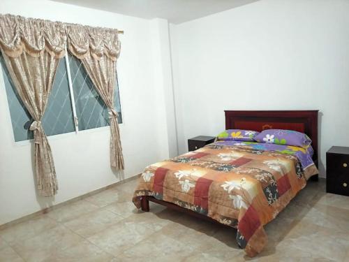 a bedroom with a bed and a window with curtains at Las Orquideas ( Rural house ) in Cumanda