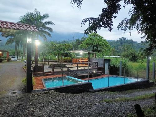 einen Pool mit einem Tisch und einem Pavillon daneben in der Unterkunft Las Orquideas ( Rural house ) in Cumanda