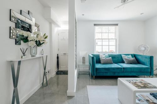 a living room with a blue couch and a table at Exceptional Whole House Chelsea with Roof Terrace in London