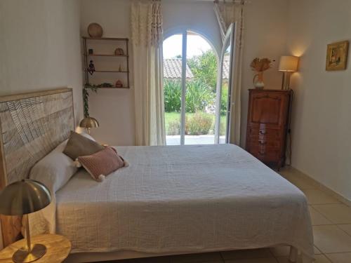 une chambre avec un grand lit et une fenêtre dans l'établissement Villa Lou Penequet, à Saint-Aygulf