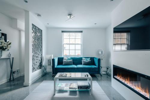 a living room with a blue couch and a fireplace at Exceptional Whole House Chelsea with Roof Terrace in London