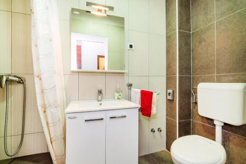 a white bathroom with a toilet and a sink at Selak Apartments in Grabovac