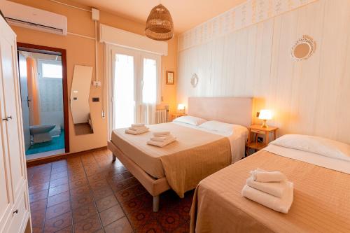 a hotel room with two beds and a bathroom at La Villa in Cervia