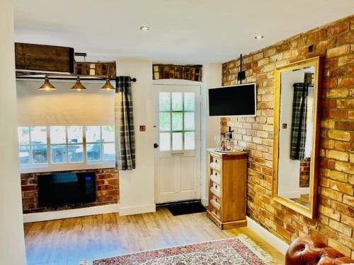 un soggiorno con parete in mattoni e TV di East Bridgford Coach House Inc Spa and Treatments a East Bridgford