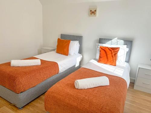 two beds with orange pillows in a room at Zen 8-Bedroom Den in Edgbaston in Birmingham