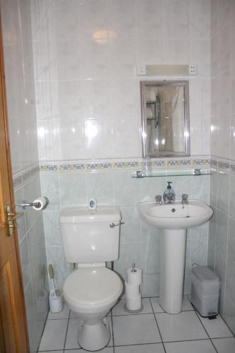 a white bathroom with a toilet and a sink at The Coach Inn in Strabane