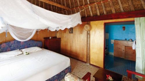 a bedroom with a white bed and a kitchen at Gold Coast Inn - Adults Only in Nanuya Lailai
