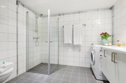 a white tiled bathroom with a shower and a toilet at The Apartments Company - Majorstuen in Oslo