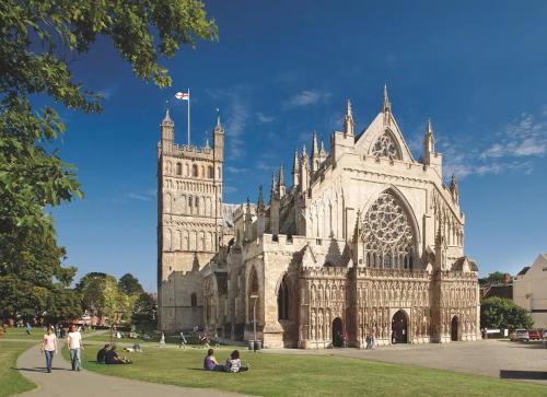 a large cathedral with people sitting in the grass at City Centre Stylish Hideaway in Exeter