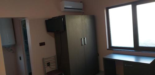 a room with a cabinet with a television and a window at Стаи за нощувки in Sliven