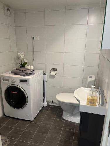 a bathroom with a washing machine and a toilet at Modernt boende med god tillgänglighet. in Alingsås