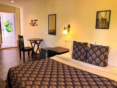 a bedroom with a bed and a table with a chair at Marari Dreamz Homestay in Mararikulam