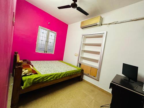 a bedroom with a bed with a pink wall at Amaravathi Home Stay in Tiruvannāmalai