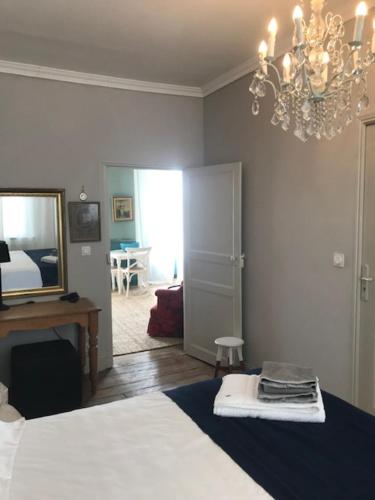 Schlafzimmer mit einem Bett, einem Spiegel und einem Kronleuchter in der Unterkunft The Apartment in Saint-Jean-dʼAngély