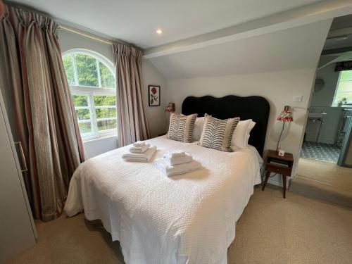 a bedroom with a white bed with towels on it at Two Luxury Cosy Cottages in Tewkesbury