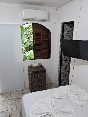 a bedroom with a bed with white sheets and a window at Pousada Familia Viva Trindade in Trindade