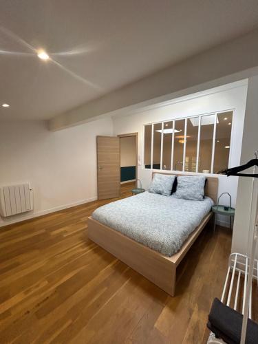 a bedroom with a large bed and wooden floors at Le Rive Droite proche gare parking facile in Montauban