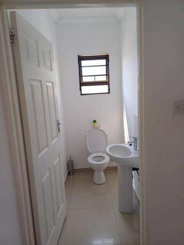 a white bathroom with a toilet and a sink at Lot 15168 Zeerust Road in Tlokweng