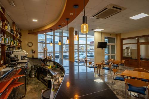 a restaurant with a bar with tables and chairs at Hotel Bartos in Almussafes